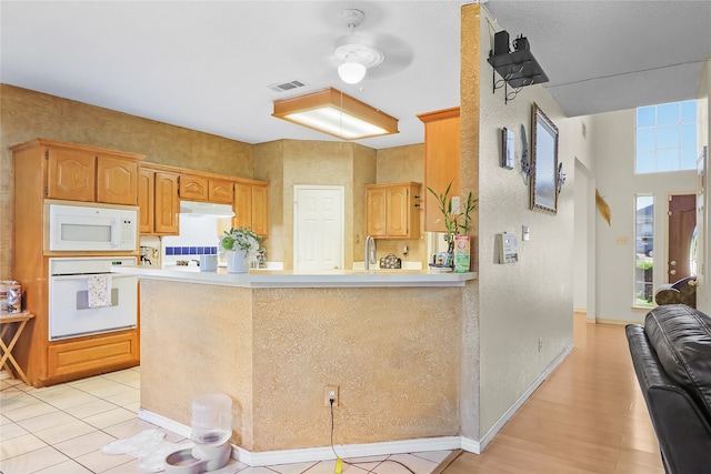 kitchen with kitchen peninsula, sink, ceiling fan, light wood-type flooring, and white appliances