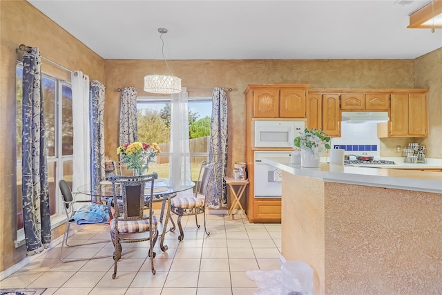 kitchen with decorative light fixtures, light tile patterned flooring, white appliances, and an inviting chandelier