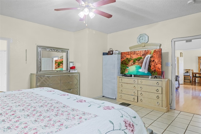 bedroom featuring a textured ceiling, light tile patterned floors, and ceiling fan