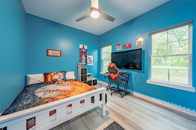 bedroom with multiple windows, wood-type flooring, and ceiling fan