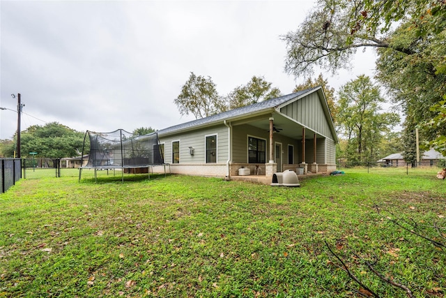 back of property featuring a yard and a trampoline