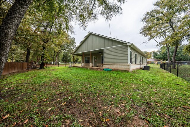 back of house with central AC, ceiling fan, and a yard