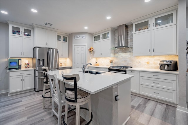 kitchen featuring white cabinetry, stainless steel appliances, sink, and wall chimney range hood