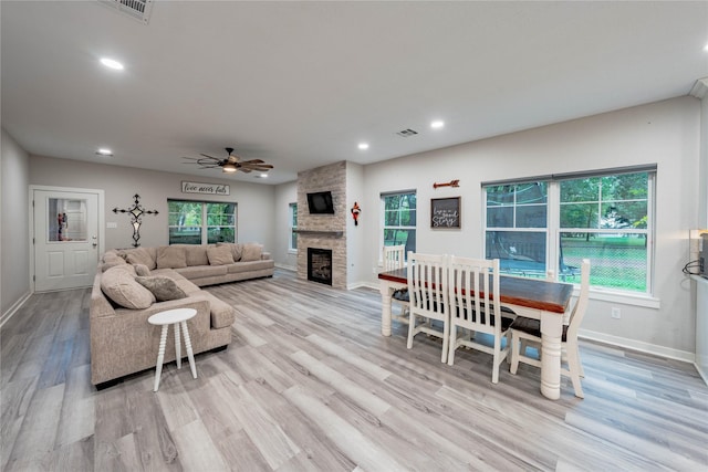 living room featuring a fireplace, ceiling fan, and light wood-type flooring