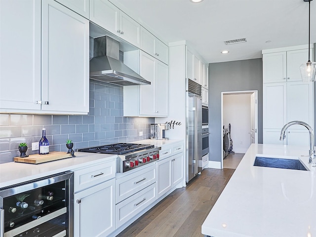 kitchen with white cabinetry, beverage cooler, stainless steel gas cooktop, extractor fan, and hardwood / wood-style flooring