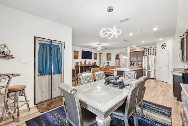 dining space featuring ceiling fan with notable chandelier and light wood-type flooring