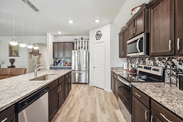 kitchen featuring stainless steel appliances, sink, tasteful backsplash, light hardwood / wood-style flooring, and pendant lighting