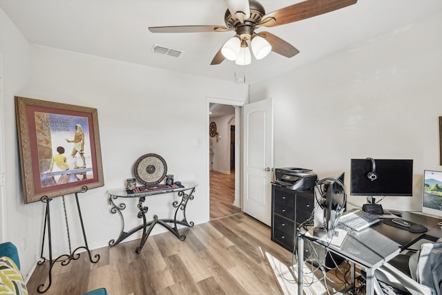 home office with light wood-type flooring and ceiling fan