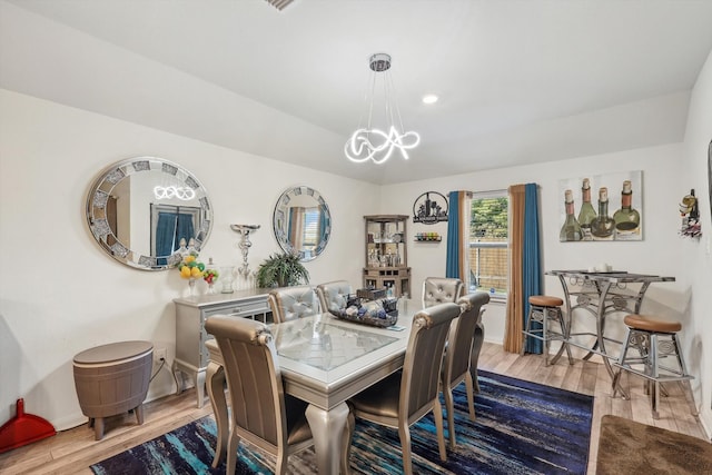 dining space with light hardwood / wood-style floors and an inviting chandelier