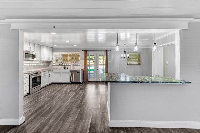 kitchen featuring appliances with stainless steel finishes, ornamental molding, hanging light fixtures, white cabinets, and dark hardwood / wood-style flooring