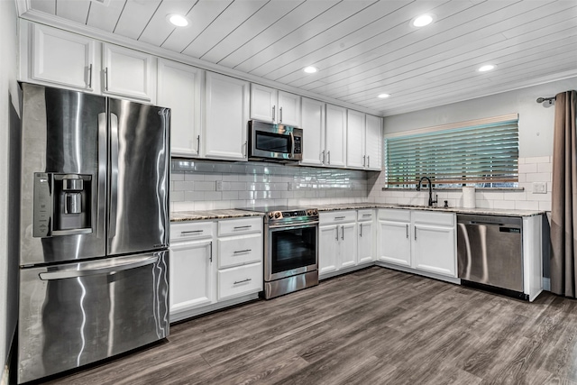 kitchen with light stone counters, white cabinetry, appliances with stainless steel finishes, sink, and dark wood-type flooring