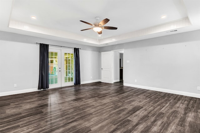 empty room with dark wood-type flooring, french doors, ceiling fan, and a raised ceiling