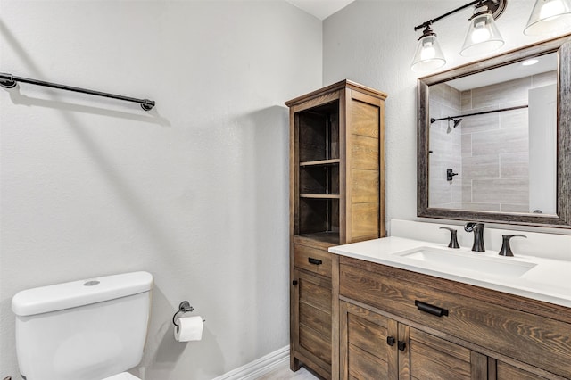 bathroom featuring a tile shower, vanity, and toilet