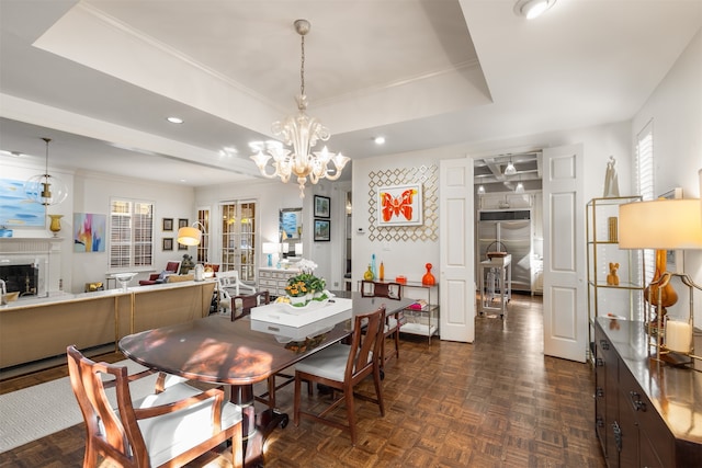 dining space featuring ornamental molding, a tray ceiling, a chandelier, and dark parquet floors