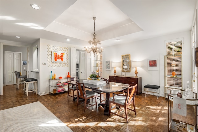 dining space featuring a raised ceiling, dark parquet floors, and a notable chandelier