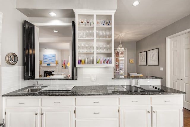 bar featuring black electric cooktop, dark stone counters, sink, and white cabinets