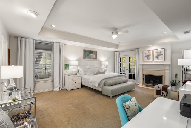 bedroom with a raised ceiling, light colored carpet, access to exterior, and ceiling fan