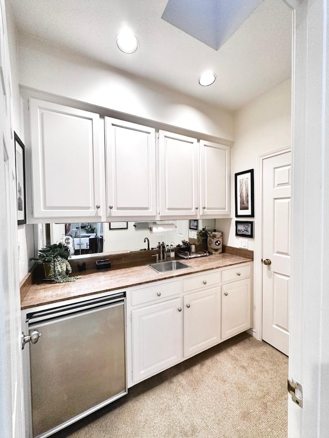 kitchen featuring white cabinetry, fridge, sink, and light carpet