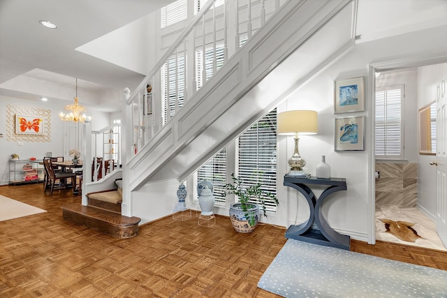 staircase with parquet flooring and a notable chandelier