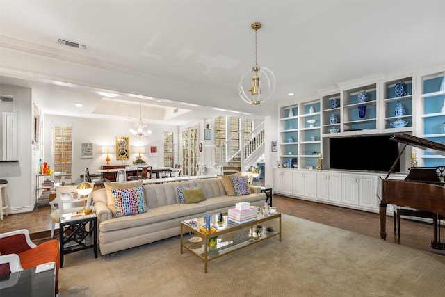 living room featuring a chandelier, a raised ceiling, and built in shelves