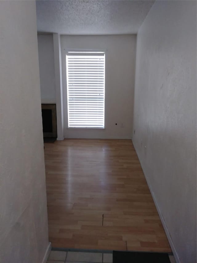 unfurnished room featuring light wood-type flooring and a textured ceiling