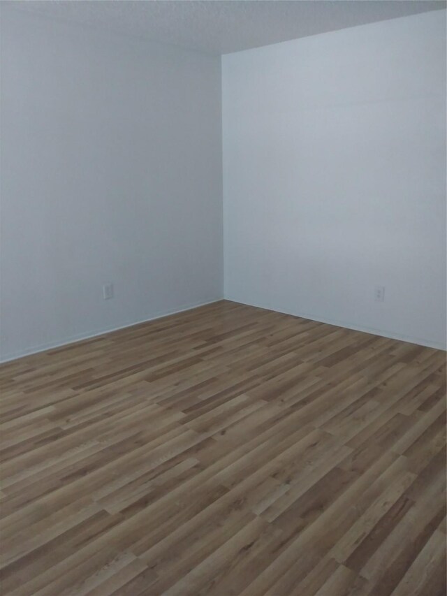 unfurnished room featuring a textured ceiling and light hardwood / wood-style floors