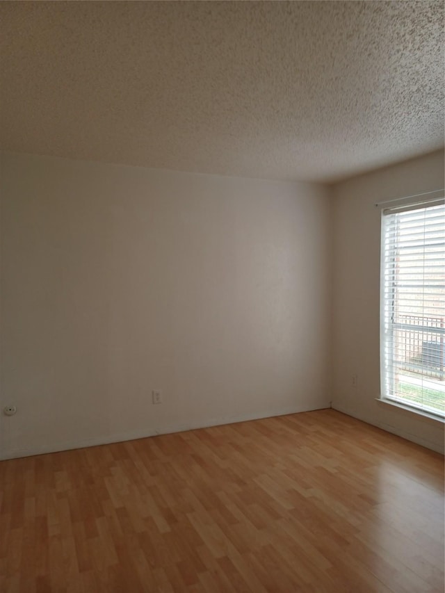 unfurnished room featuring light hardwood / wood-style floors and a textured ceiling