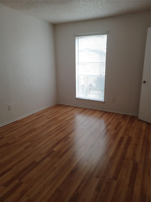 spare room featuring dark hardwood / wood-style flooring and a textured ceiling