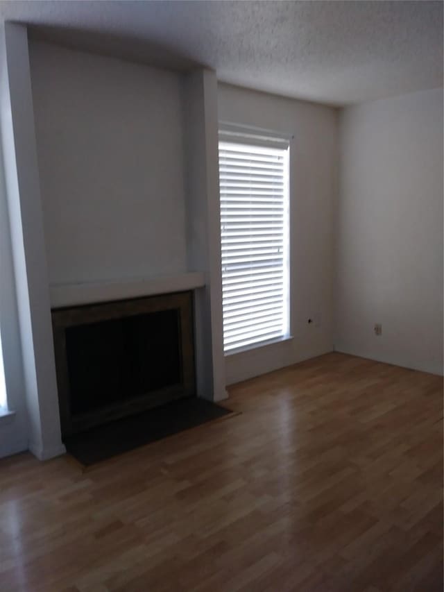 unfurnished living room featuring wood-type flooring and a textured ceiling