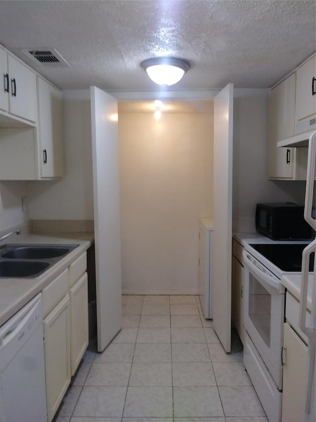 kitchen with light tile patterned flooring, white appliances, sink, and white cabinets