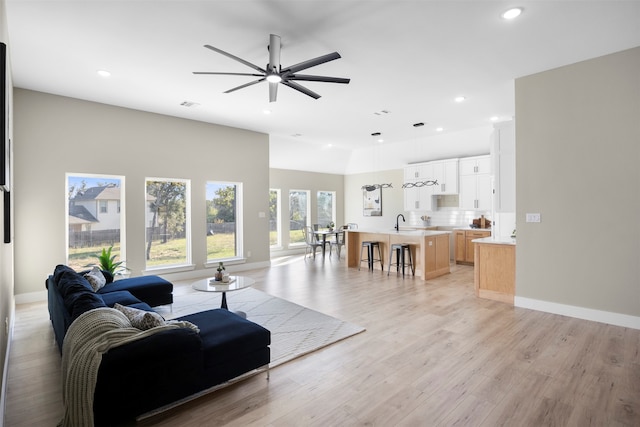 living room featuring light wood-type flooring, sink, and ceiling fan