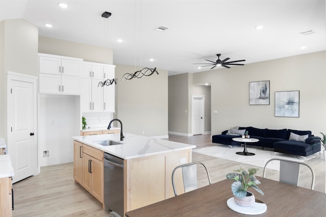 kitchen with hanging light fixtures, sink, light hardwood / wood-style floors, dishwasher, and a kitchen island with sink