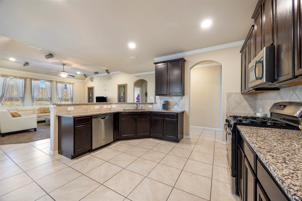 kitchen featuring light stone countertops, crown molding, stainless steel appliances, and light tile patterned flooring