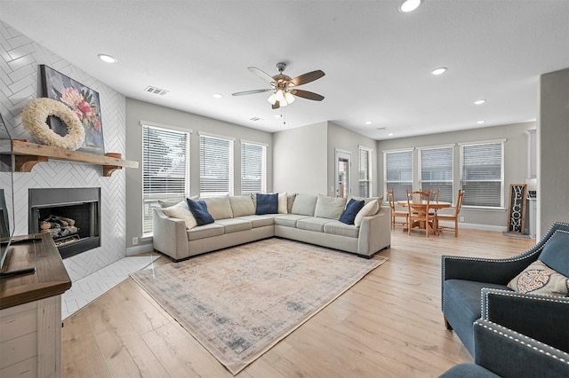 living room featuring a fireplace, light hardwood / wood-style flooring, and ceiling fan