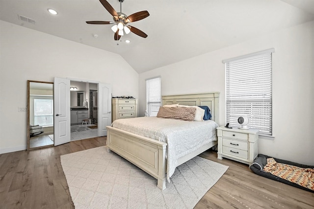 bedroom with ceiling fan, lofted ceiling, connected bathroom, and light hardwood / wood-style floors