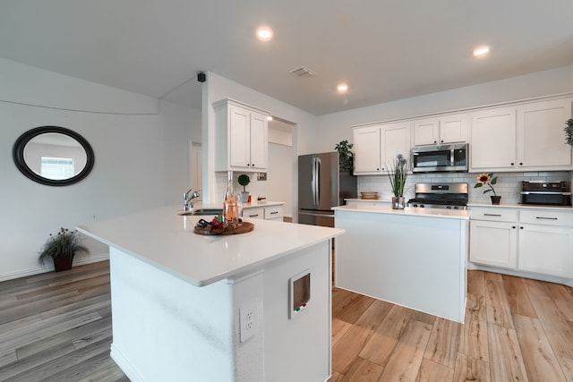 kitchen featuring white cabinetry, a kitchen island, stainless steel appliances, and light wood-type flooring