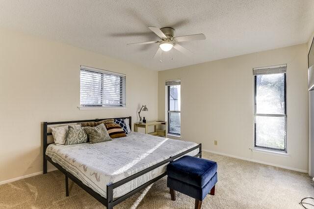 carpeted bedroom featuring ceiling fan and a textured ceiling