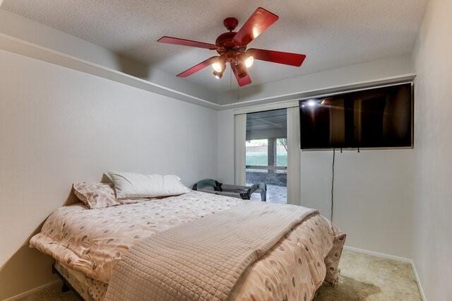 bedroom featuring ceiling fan, light colored carpet, and a textured ceiling