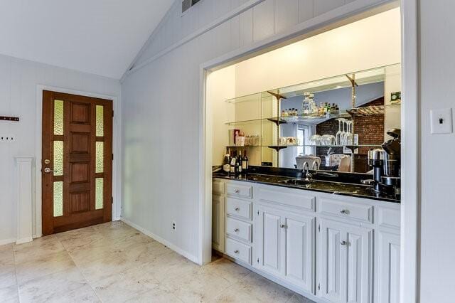 bar with sink, white cabinets, and lofted ceiling