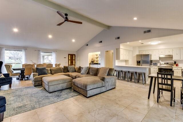 living room featuring ceiling fan, high vaulted ceiling, and beam ceiling