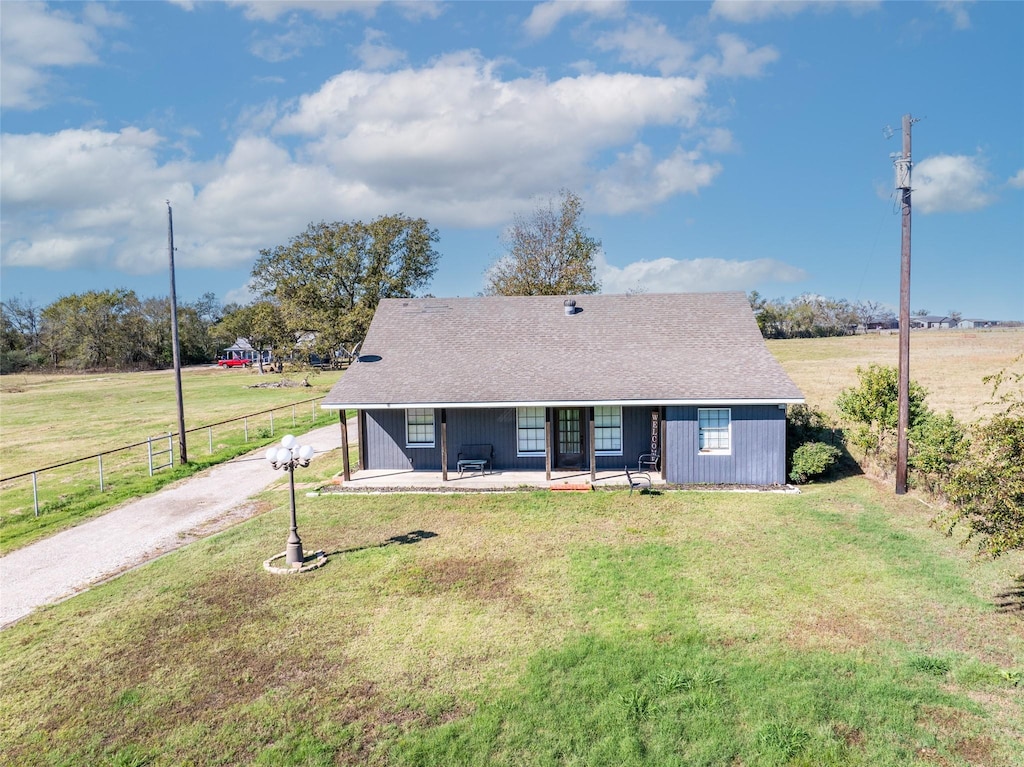 ranch-style home with a porch, a front lawn, and a rural view