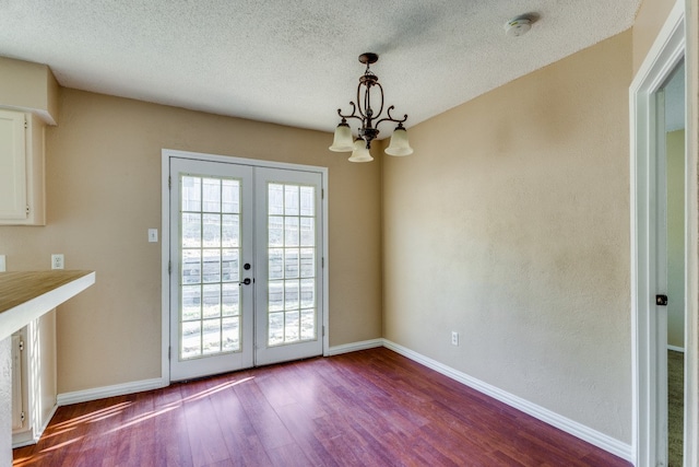 doorway to outside with a notable chandelier, hardwood / wood-style flooring, french doors, and a textured ceiling