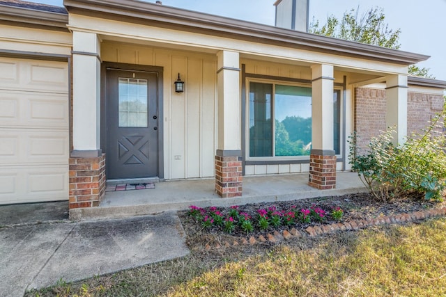 view of exterior entry featuring a garage and a porch