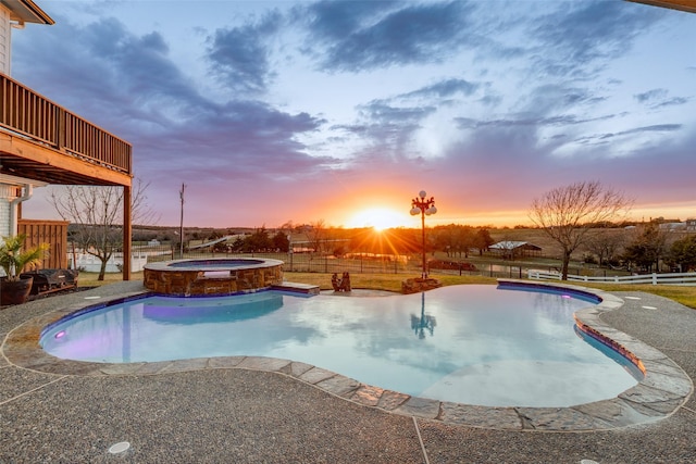 pool at dusk with an in ground hot tub