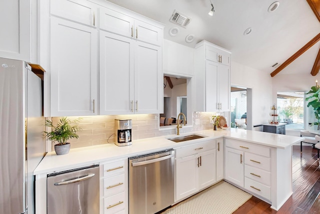 kitchen featuring sink, kitchen peninsula, decorative backsplash, white cabinets, and appliances with stainless steel finishes