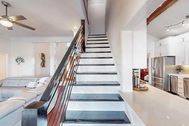 stairs featuring crown molding, track lighting, and ceiling fan