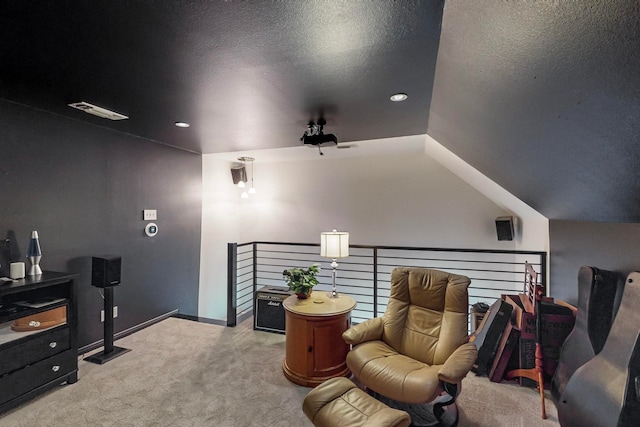 living area with light carpet, lofted ceiling, and a textured ceiling