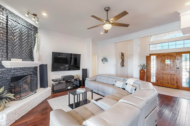 living room with ceiling fan, decorative columns, dark hardwood / wood-style floors, a fireplace, and ornamental molding