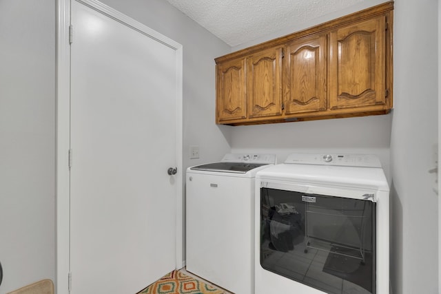 clothes washing area with cabinets, a textured ceiling, and separate washer and dryer