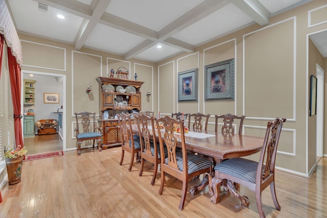 dining space with light wood-type flooring, coffered ceiling, and beamed ceiling